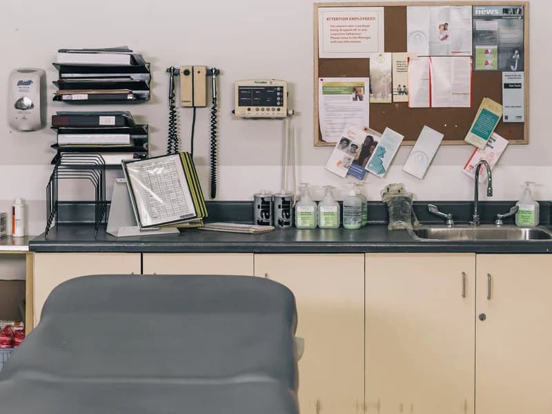 Examination table beside clinical equipment and supplies in a treatment room