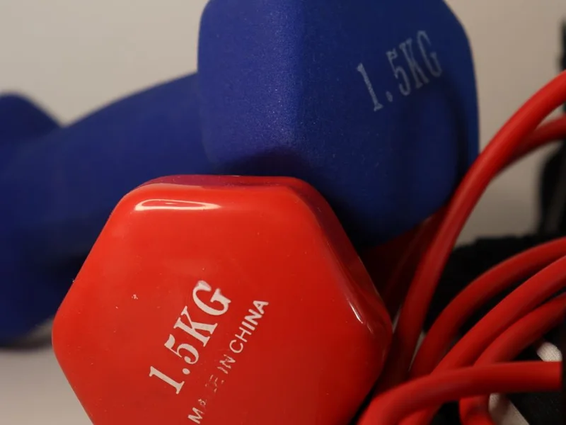 Light exercise dumbbells and a resistance band on a white surface